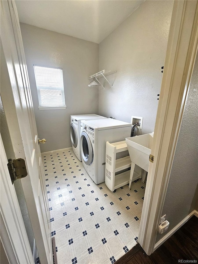 washroom featuring washer and dryer, a sink, laundry area, and baseboards