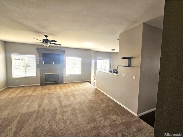 unfurnished living room with a tiled fireplace, carpet floors, and baseboards