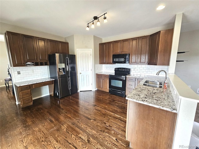 kitchen with dark wood-style floors, backsplash, a sink, light stone countertops, and black appliances