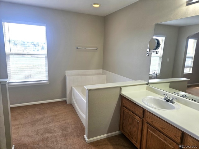 full bath with a bath, vanity, and baseboards