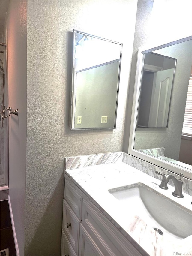 bathroom with a textured wall and vanity