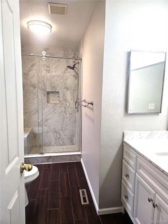 bathroom featuring a stall shower, wood finish floors, vanity, and visible vents