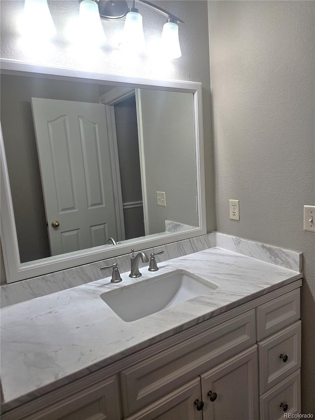 bathroom featuring a textured wall and vanity