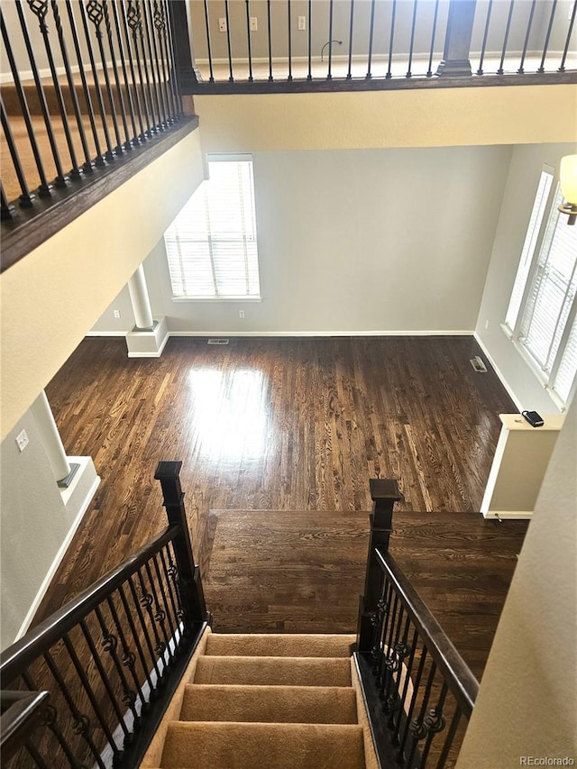 stairway featuring wood finished floors, baseboards, and a wealth of natural light