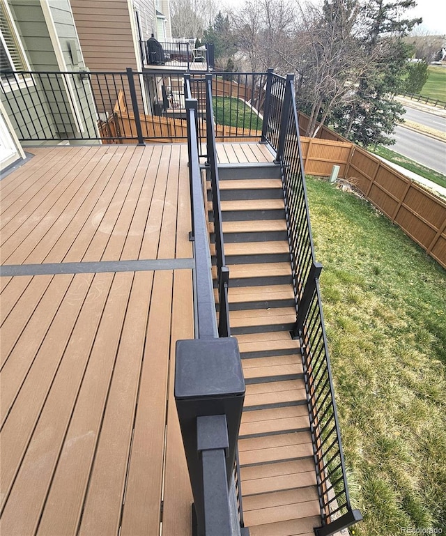 deck featuring stairway, fence, and a lawn