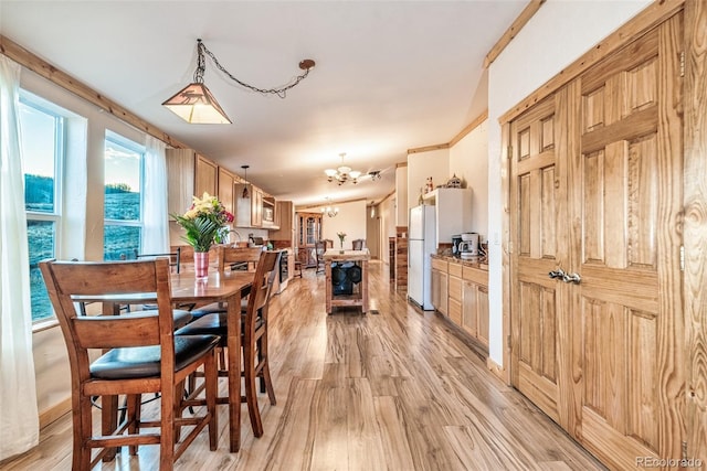 dining space with a chandelier, ornamental molding, and light hardwood / wood-style flooring