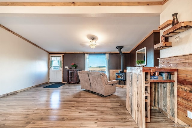 living room with light wood-type flooring, crown molding, and a wood stove