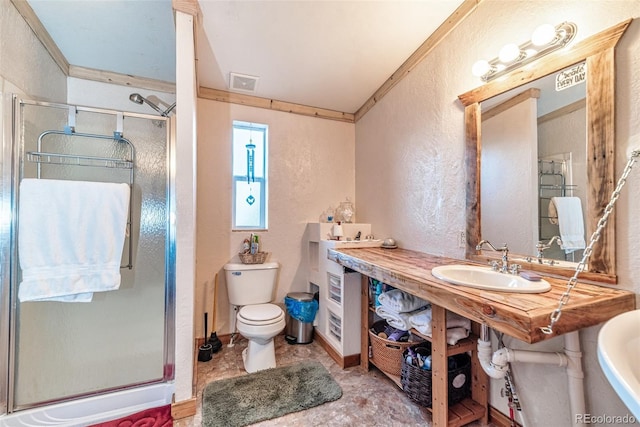 bathroom featuring sink, toilet, a shower with door, and ornamental molding