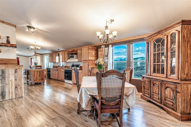 dining space featuring a notable chandelier, light wood-type flooring, and vaulted ceiling