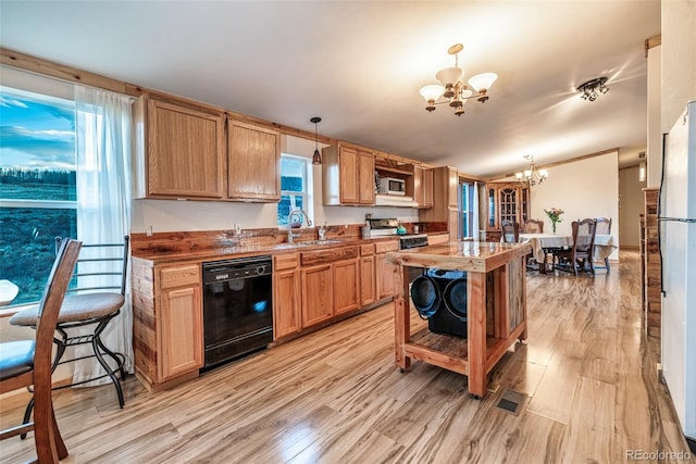 kitchen featuring dishwasher, light wood-style flooring, an inviting chandelier, gas stove, and a sink