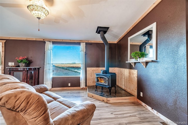 living area with baseboards, wood finished floors, a wood stove, and a textured wall