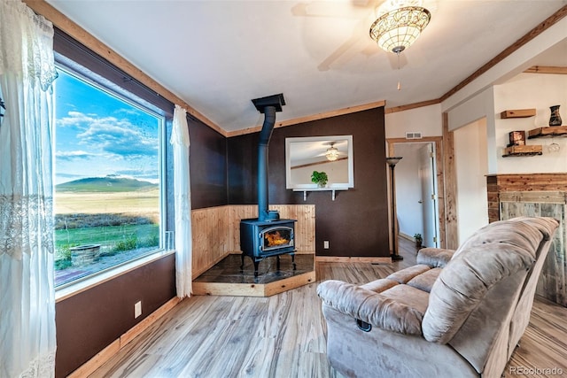 interior space with visible vents, ceiling fan, lofted ceiling, a wood stove, and wood finished floors