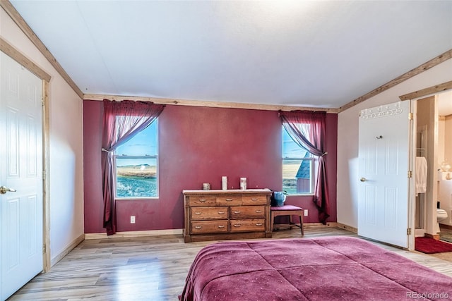 bedroom with light wood-style flooring, ensuite bath, and baseboards