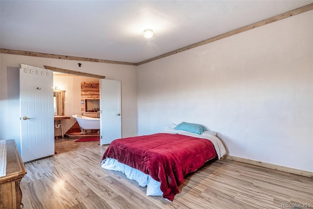 bedroom with ensuite bath and wood finished floors