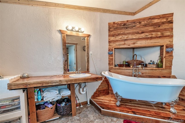 bathroom featuring a freestanding bath, a textured wall, and a sink