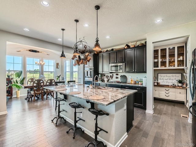607 Azalea St, Brighton, CO 80601 - kitchen featuring appliances with stainless steel finishes, a chandelier, a textured ceiling, a kitchen breakfast bar, and plenty of natural light