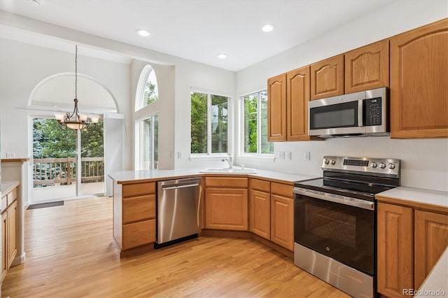 11237 W Ford Dr, Lakewood, CO 80226 - kitchen featuring appliances with stainless steel finishes, light wood-type flooring, light countertops, a chandelier, and pendant lighting