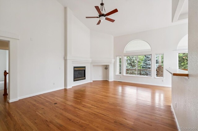 11237 W Ford Dr, Lakewood, CO 80226 - unfurnished living room with high vaulted ceiling, light wood-style floors, ceiling fan, and a large fireplace