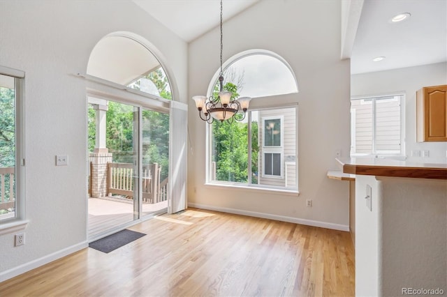 11237 W Ford Dr, Lakewood, CO 80226 - unfurnished dining area with healthy amount of natural light, wood finished floors, a chandelier, and high vaulted ceiling