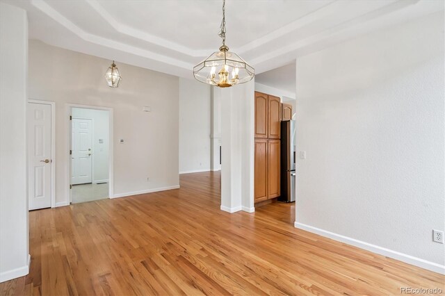 11237 W Ford Dr, Lakewood, CO 80226 - spare room with a chandelier, light wood finished floors, and a raised ceiling