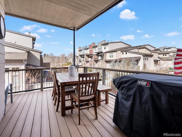 wooden terrace with a residential view, outdoor dining area, and grilling area