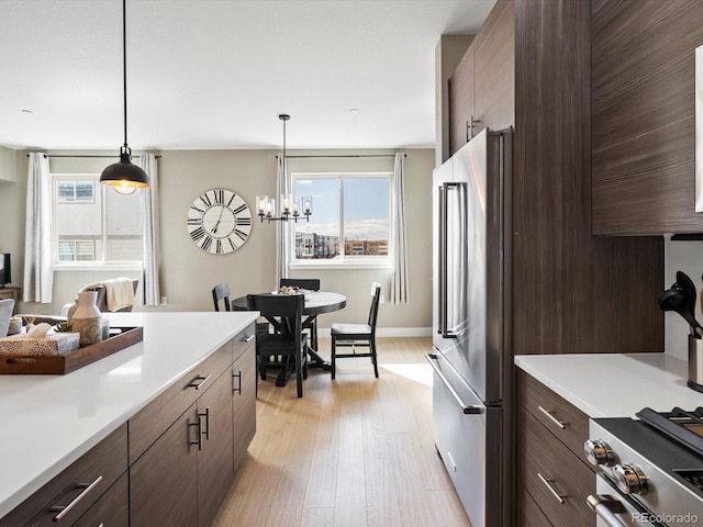 kitchen featuring light wood-style flooring, appliances with stainless steel finishes, light countertops, and dark brown cabinets