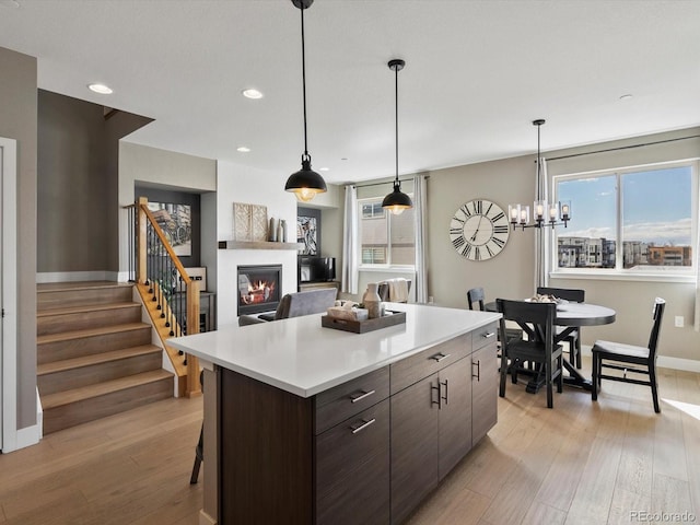 kitchen featuring a healthy amount of sunlight, light wood-style floors, light countertops, and a glass covered fireplace