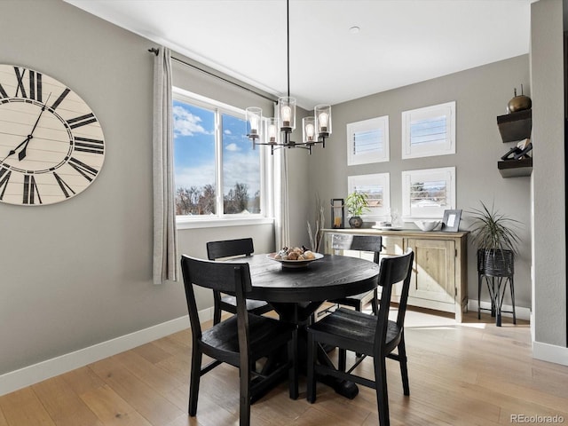 dining space featuring a chandelier, light wood finished floors, and baseboards