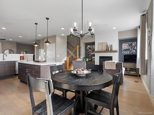 dining area featuring recessed lighting, a fireplace, stairway, and light wood finished floors