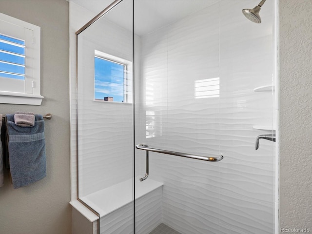 bathroom with a stall shower and a textured wall