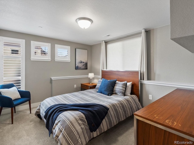 carpeted bedroom with visible vents, a textured ceiling, and baseboards