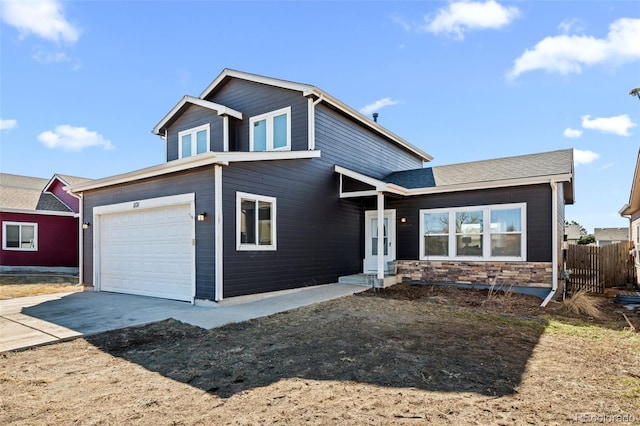 traditional-style house featuring an attached garage, stone siding, fence, and concrete driveway