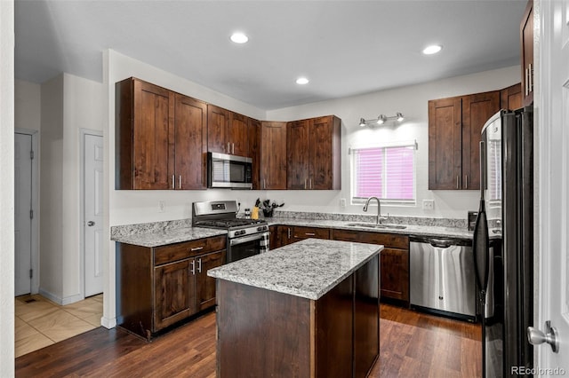 kitchen with stainless steel appliances, dark wood-type flooring, a sink, and a center island