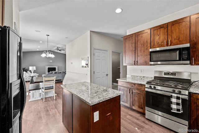 kitchen with a notable chandelier, stainless steel appliances, open floor plan, vaulted ceiling, and light wood finished floors