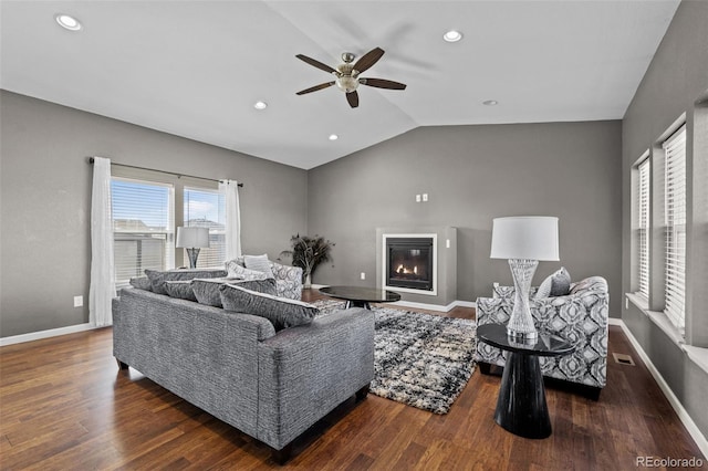 living room featuring lofted ceiling, baseboards, wood finished floors, and a glass covered fireplace