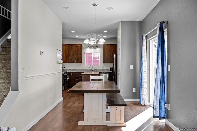 kitchen with a sink, dark wood-type flooring, stainless steel range with gas cooktop, and baseboards