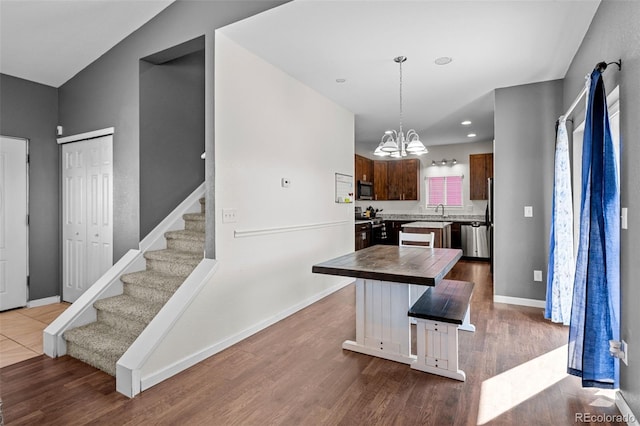 kitchen featuring a chandelier, wood finished floors, baseboards, appliances with stainless steel finishes, and a center island