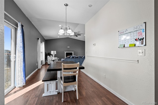 dining space featuring dark wood-style flooring, a notable chandelier, vaulted ceiling, and baseboards