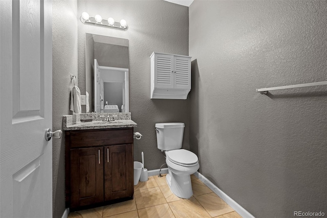 bathroom featuring toilet, vanity, baseboards, and tile patterned floors