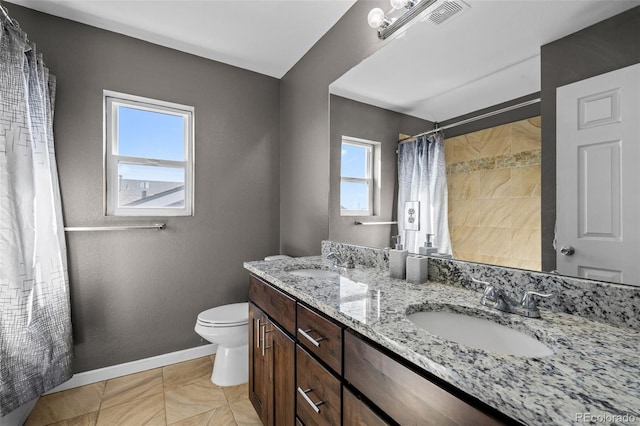 full bath with baseboards, a sink, toilet, and double vanity