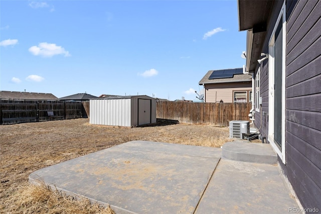 view of yard featuring a patio, a fenced backyard, an outbuilding, a storage unit, and central AC