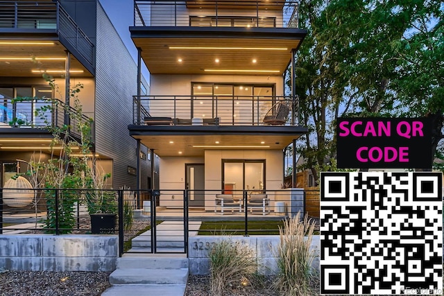 exterior space featuring stucco siding, a balcony, and fence