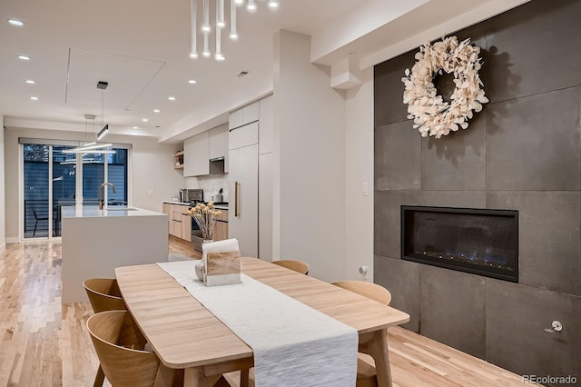 dining area featuring a fireplace, recessed lighting, and light wood-type flooring