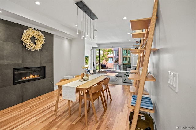 dining space with a tiled fireplace, recessed lighting, and wood finished floors