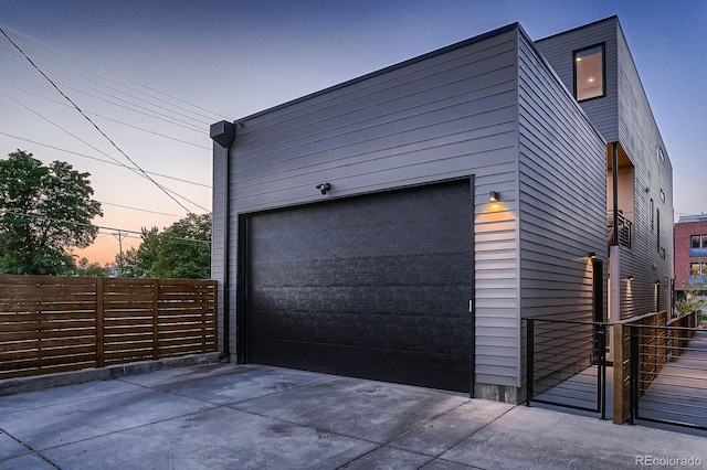 garage at dusk with fence and driveway