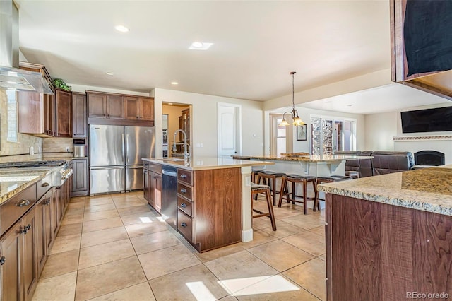 7172 S Oakleaf St, Bennett, CO 80102 - kitchen with an island with sink, wall chimney exhaust hood, a kitchen bar, a sink, and stainless steel appliances