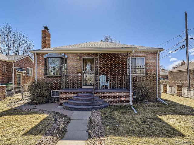 bungalow-style house featuring brick siding, a chimney, a front yard, and fence