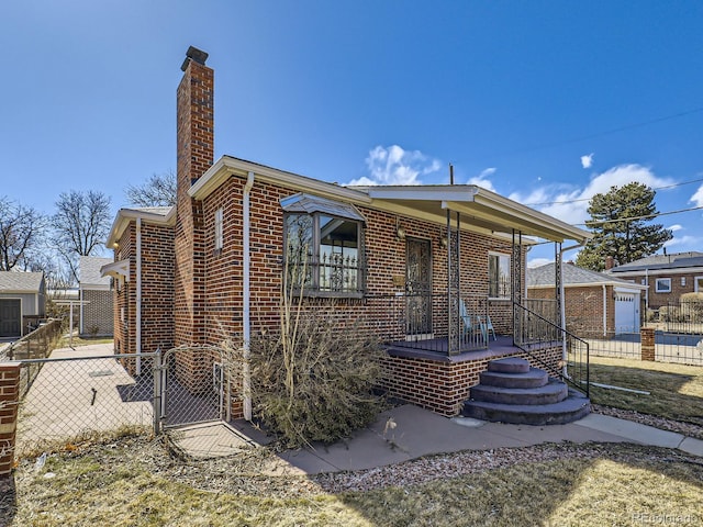 view of front of home with a gate, a chimney, fence, and brick siding