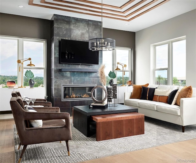 living room with a fireplace, tile walls, a chandelier, and light wood-type flooring