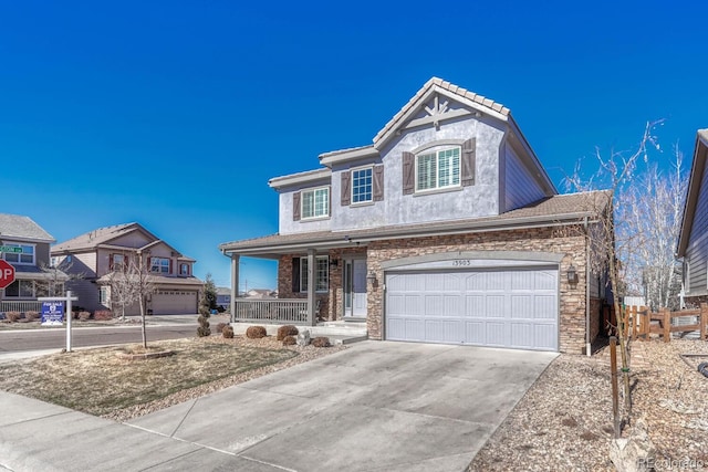 view of front facade with a porch, concrete driveway, stone siding, and a garage